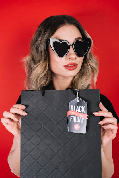 Free photo woman with heart sunglasses and black friday bag