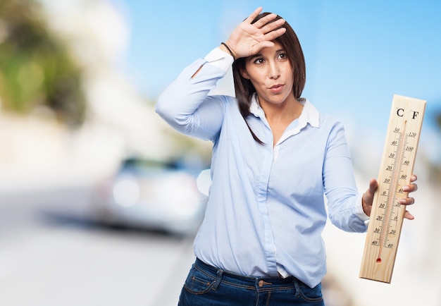 Free photo woman with heat holding a large thermometer