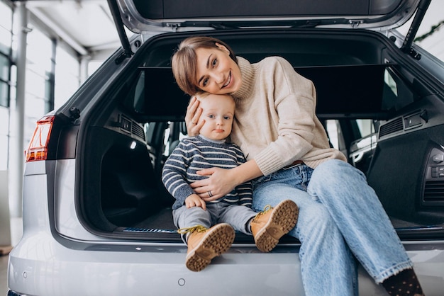 Woman with her son sitting in car trunk in a car showroom