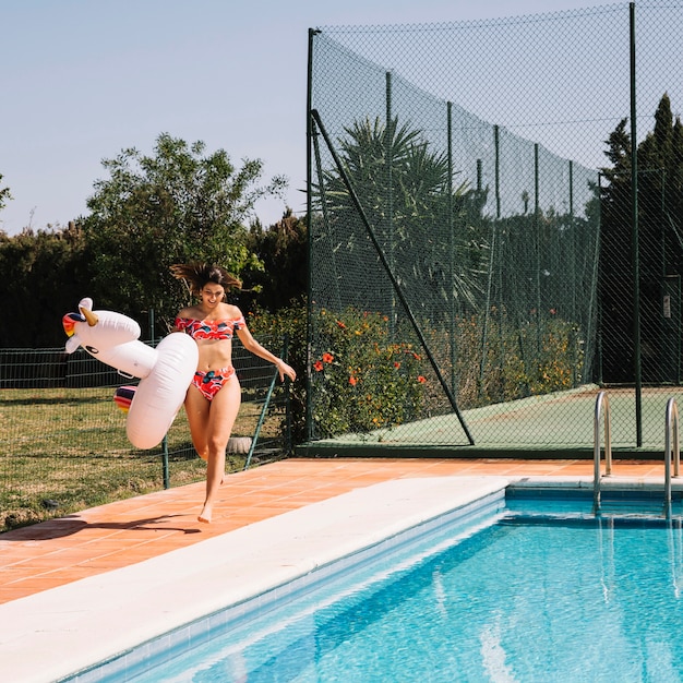 Woman with inflatable unicorn next to pool