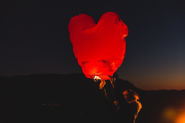 Free photo woman with a kite of hot air at night