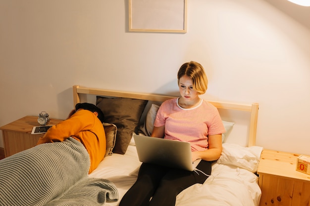 Free photo woman with laptop near sleeping husband