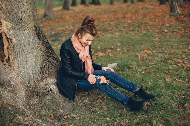 Free photo woman with a leg injury. the wounded girl sitting by the tree. the wound is bleeding.