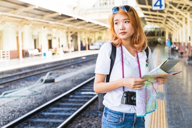 Woman with map and digital camera on platform