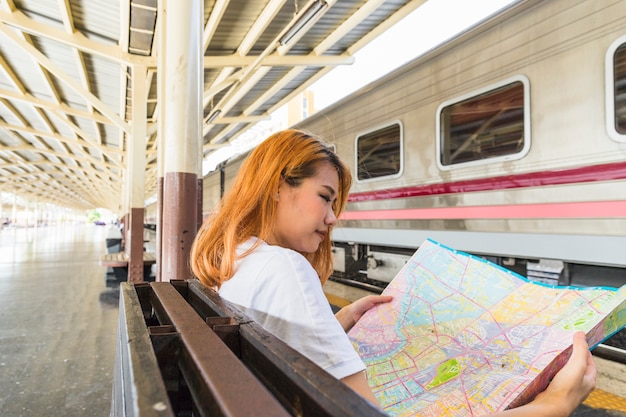 Free photo woman with map on seat near train on platform