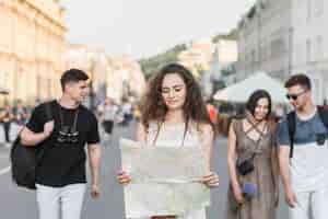 Free photo woman with map walking with friends on street