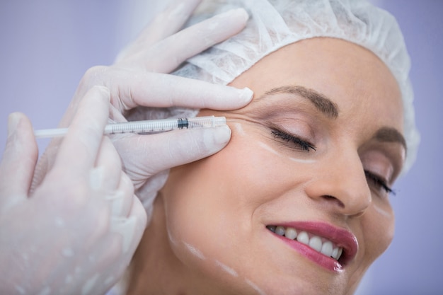 Woman with marked face receiving botox injection