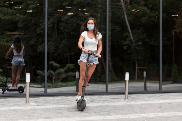 Woman with mask riding an electric scooter