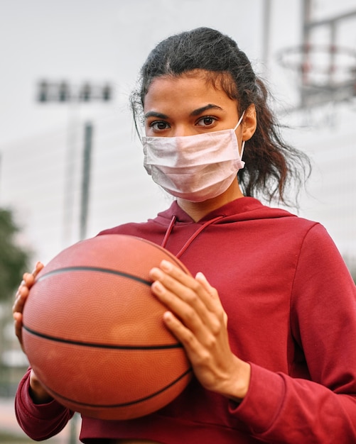 Woman with medical mask holding a basketball