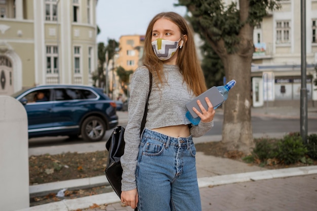 Woman with medical mask holding a bottle of water