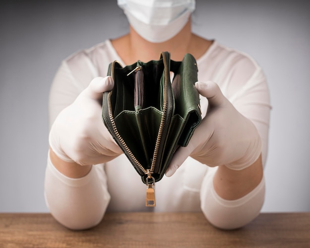 Free photo woman with medical mask holding an empty wallet