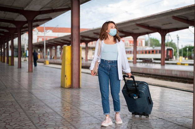 Free photo woman with medical mask and luggage at the public train station