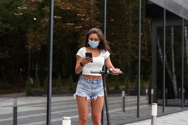 Woman with medical mask and scooter outdoors