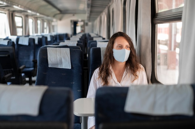 Free photo woman with medical mask traveling by train during the pandemic