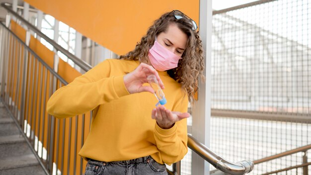 Woman with medical mask and using hand sanitizer