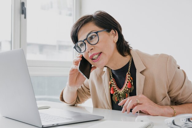 Woman with necklace talking on the phone on her office