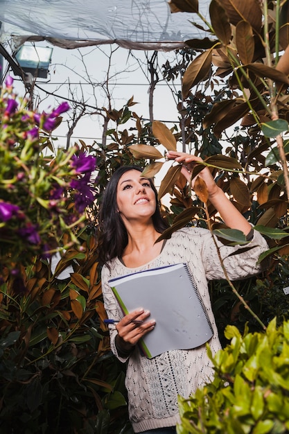 Free Photo woman with notebook inspecting flowers