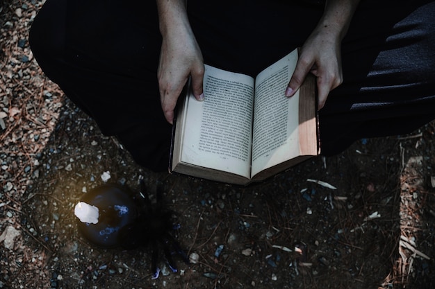 Free Photo woman with opened book and candle on forest ground