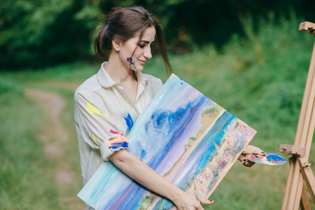 Free photo woman with paint stained t-shirt with a picture in her hand