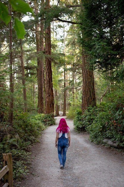 Woman with pink hair walking through the path in the forest