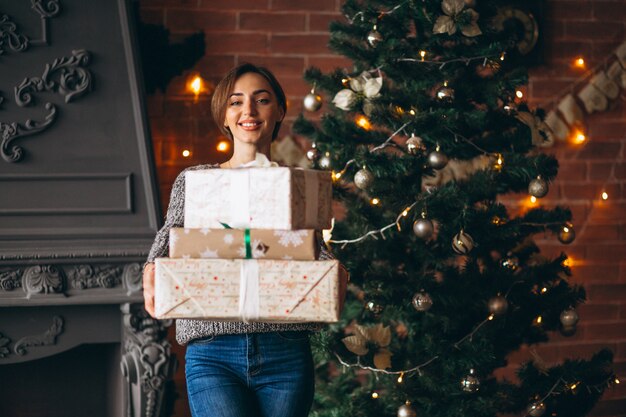 Woman with presents standing in front of christmas tree