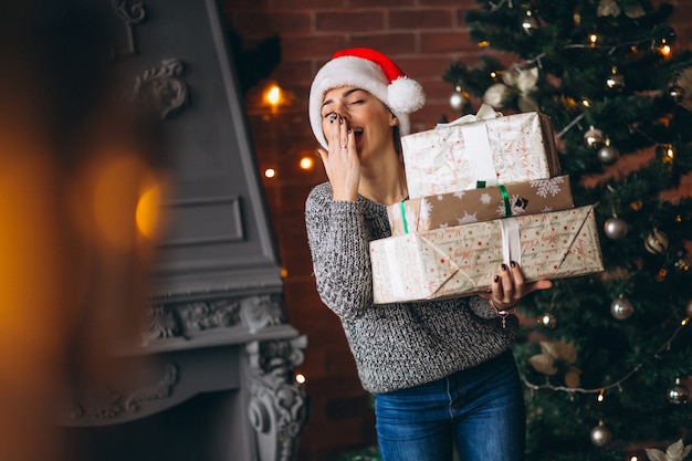 Woman with presents standing in front of christmas tree