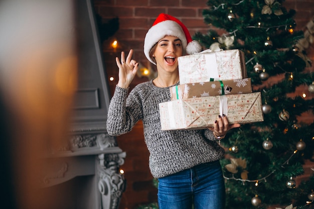 Woman with presents standing in front of christmas tree