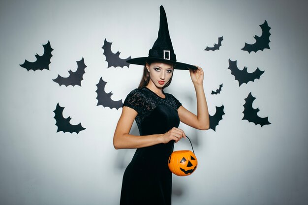 Woman with pumpkin touching hat