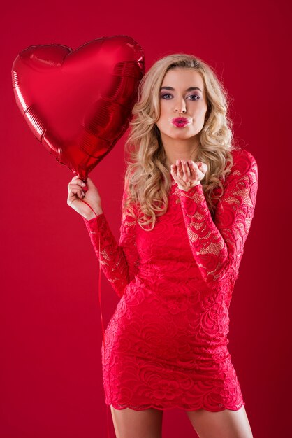 Woman with red balloon blowing a kiss