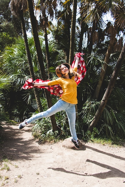 Free photo woman with red scarf jumping near palms