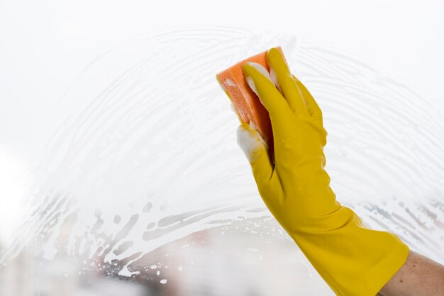 Woman with rubber glove cleaning window