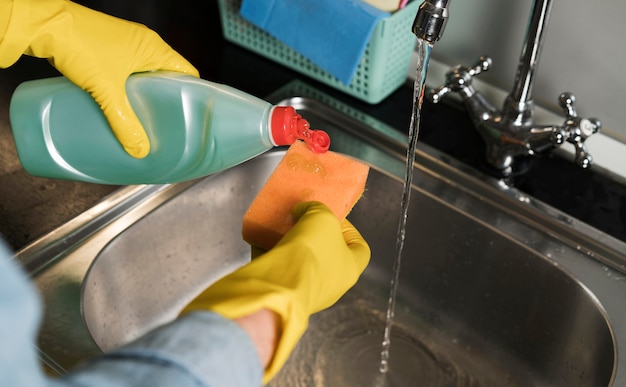 Free photo woman with rubber gloves cleaning the sink