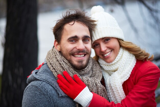 Woman with scarf and wool hat hugging her boyfriend