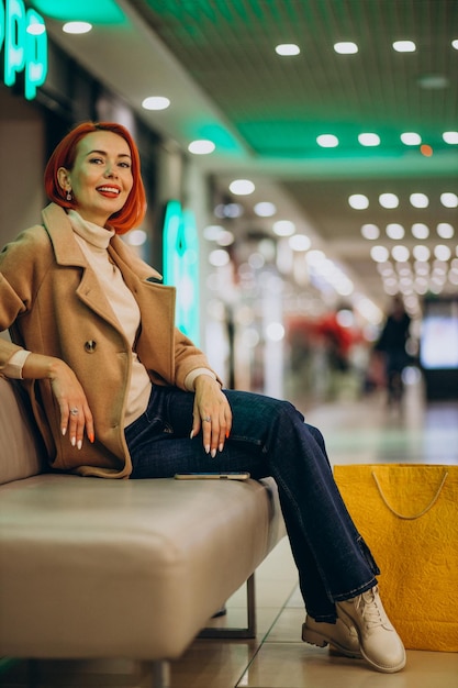 Free photo woman with shopping bags sitting on coach in shopping mall