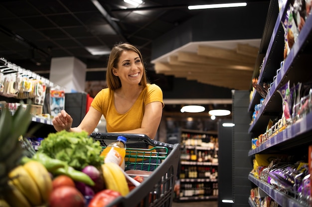 Woman with shopping cart buying food at supermarket