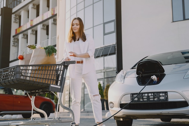 Free photo woman with a shopping cart by her car