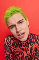 Free photo woman with short green hair reacts on something unpleasant hears offensive words wears casual jumper on red