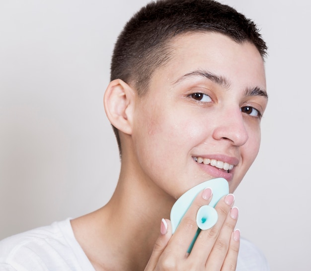 Free Photo woman with short hair cleaning her face while looking at the camera