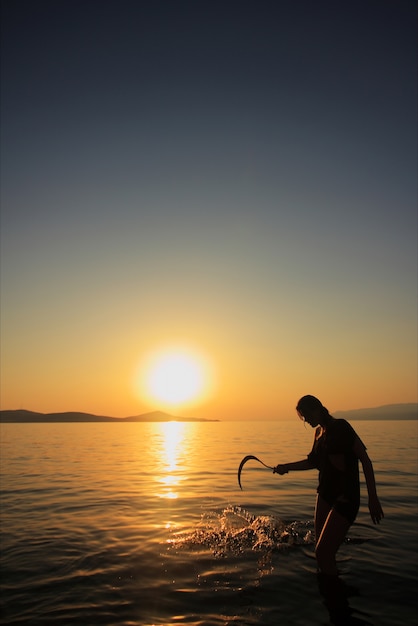 Woman with a sickle on the beach at sunset