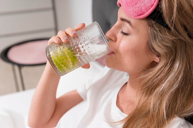 Woman with sleep mask holding a glass of water and lime