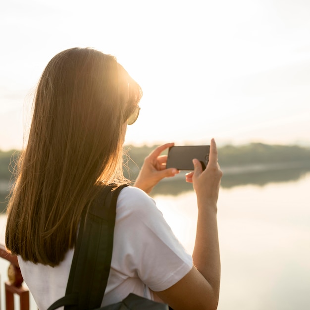 Free Photo woman with smartphone photographing the view while traveling