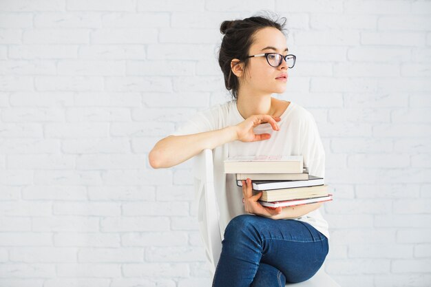 Woman with stack of books on chair