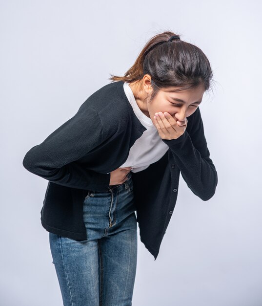 A woman with a stomachache puts her hands on her stomach and covers her mouth.