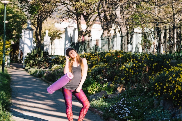 Woman with stretching mat posing in park