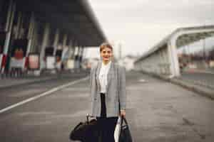 Free photo woman with suitcase standing by the airport