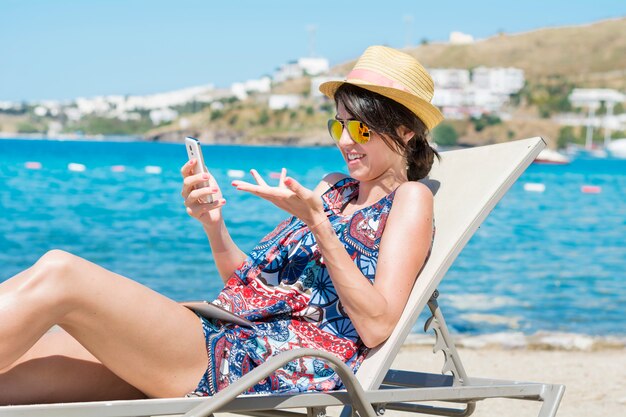 Woman with sunglasses and hat looking a mobile