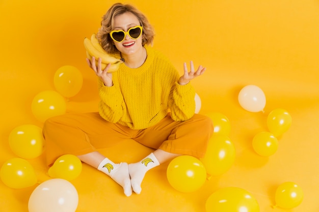 Free photo woman with sunglasses holding bananas