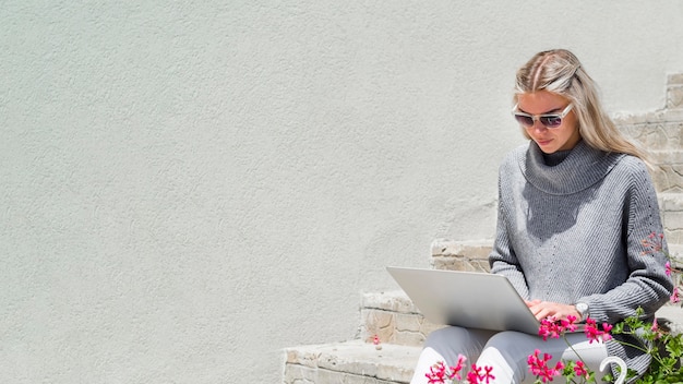 Free Photo woman with sunglasses outdoors working on laptop