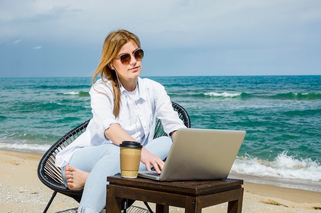 Woman with sunglasses working at the beach