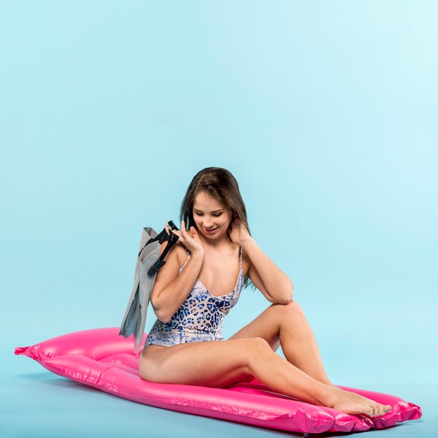 Free photo woman with swimfins on pink air mat